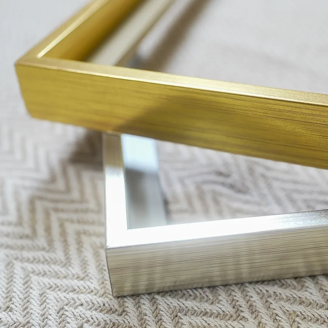 Nahaufnahme der Gehrungsecken eines goldenen und eines silbernen Aluminiumrahmens
