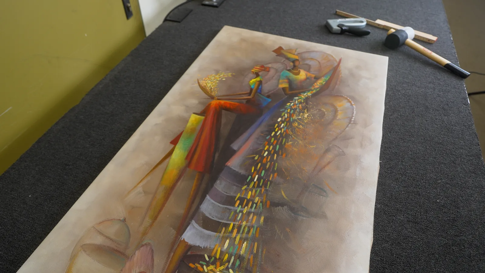 Fertig auf den Keilrahmen gespannte Leinwand auf dem Werkstatttisch, daneben Spannkeile und Holzhammer