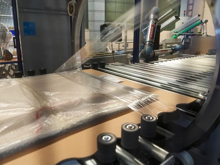 Fotolijst loopt door de verpakkingsmachine en wordt in folie verpakt