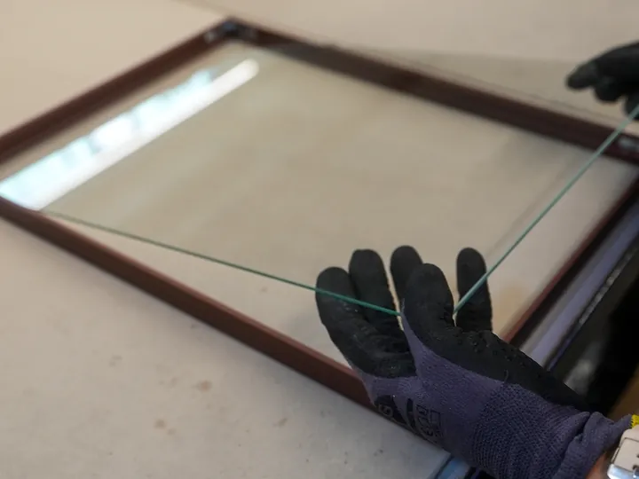 Glasplaat wordt met de hand in een fotolijst geplaatst